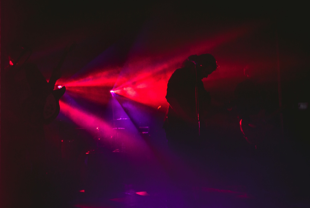 Stage with dramatic purple and gold lighting, performers silhouetted against bright backdrop